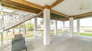 Una zona exterior coberta amb paviment de formigó, columnes blanques i una escala.