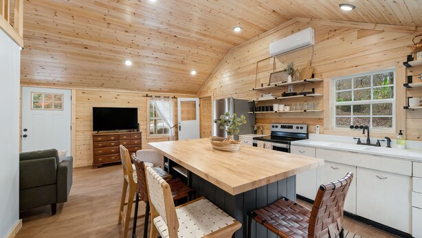 Una cocina amplia con armarios de madera, una isla central y un comedor con sillas.