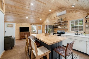 Una cocina amplia con armarios de madera, una isla central y un comedor con sillas.
