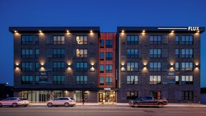 A multi-story hotel with a prominent red accent wall, multiple balconies, and a visible entrance marked '1400'. - Sleepover | Wonderful 1BD/1BA -Downtown Des Moines (Des Moines)