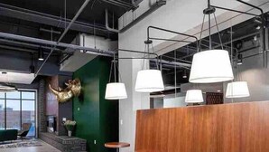 A modern interior with wooden seating, tables, and pendant lighting. - Sleepover | Wonderful 1BD/1BA -Downtown Des Moines (Des Moines)
