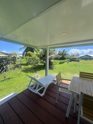 A covered outdoor area with a wooden table and two white lounge chairs. - Ânani - Mirimiri Lodge (Raiatea)