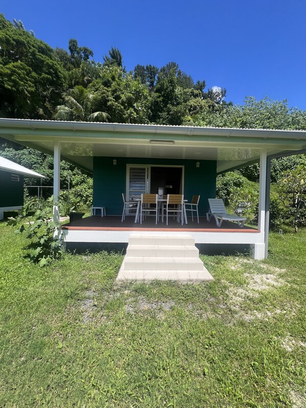 A green building with a covered porch, outdoor seating, and a staircase leading to the entrance. - Ânani - Mirimiri Lodge (Raiatea)
