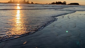 A beach at sunset with the sun reflecting on the water.