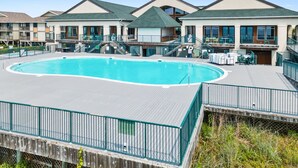 Una piscina con cubierta de madera, rodeada de edificios con balcones y ventanas amplias.