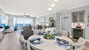 Una sala de estar moderna con comedor, ventanas amplias y vista al mar.