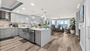 Una cocina moderna con armarios grises, una isla central y un comedor con vistas al mar.