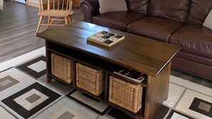 Ein gemütliches Wohnzimmer mit braunem Ledersofa, einem Holztisch, einem Holzstuhl und einem gemusterten Teppich.