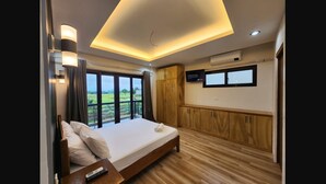 Ein modernes Schlafzimmer mit einem großen Bett, Holzboden, einem an der Wand montierten Fernseher und Blick ins Freie.