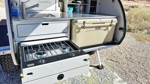 Une cuisine de taille réduite, équipée d’une cuisinière, d’un évier et de placards de rangement.