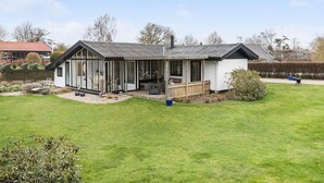 A modern house with a large glass extension, a fenced garden, and a clear sky.