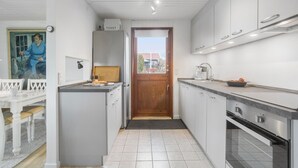 A compact kitchen with a wooden door, a sink, and a stove.