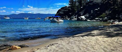 Una spiaggia con acque cristalline, barche e un litorale roccioso.