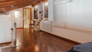 Una habitación amplia con piso de madera, un radiador y una escalera que sube a un nivel superior.