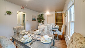 A dining area with a table set for four, surrounded by patterned chairs, a staircase, and a door marked "EXIT". - Quiet Owego Getaway Near Main Street & Riverwalk! (Owego)
