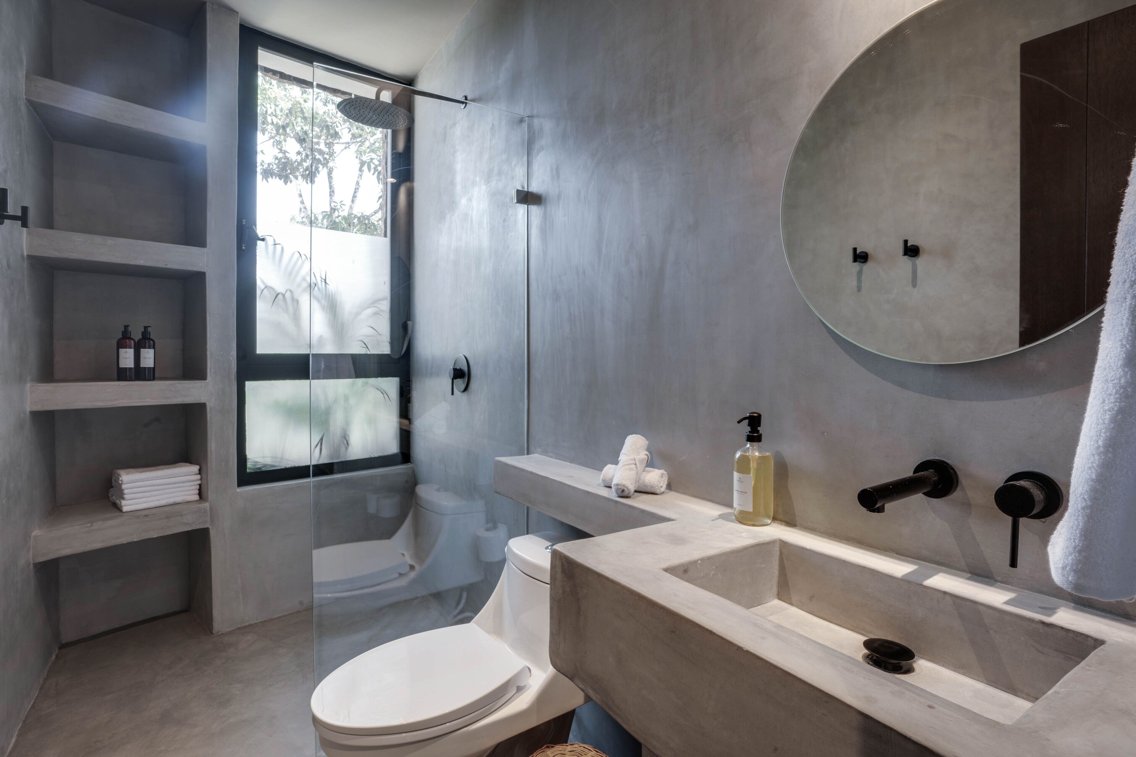 A modern bathroom with a large mirror, a beige sink, and a glass shower enclosure.