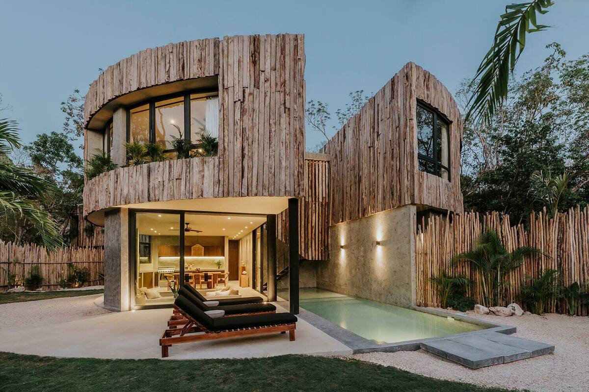 Uma casa moderna com fachada de madeira curva, cozinha visível e área de piscina.