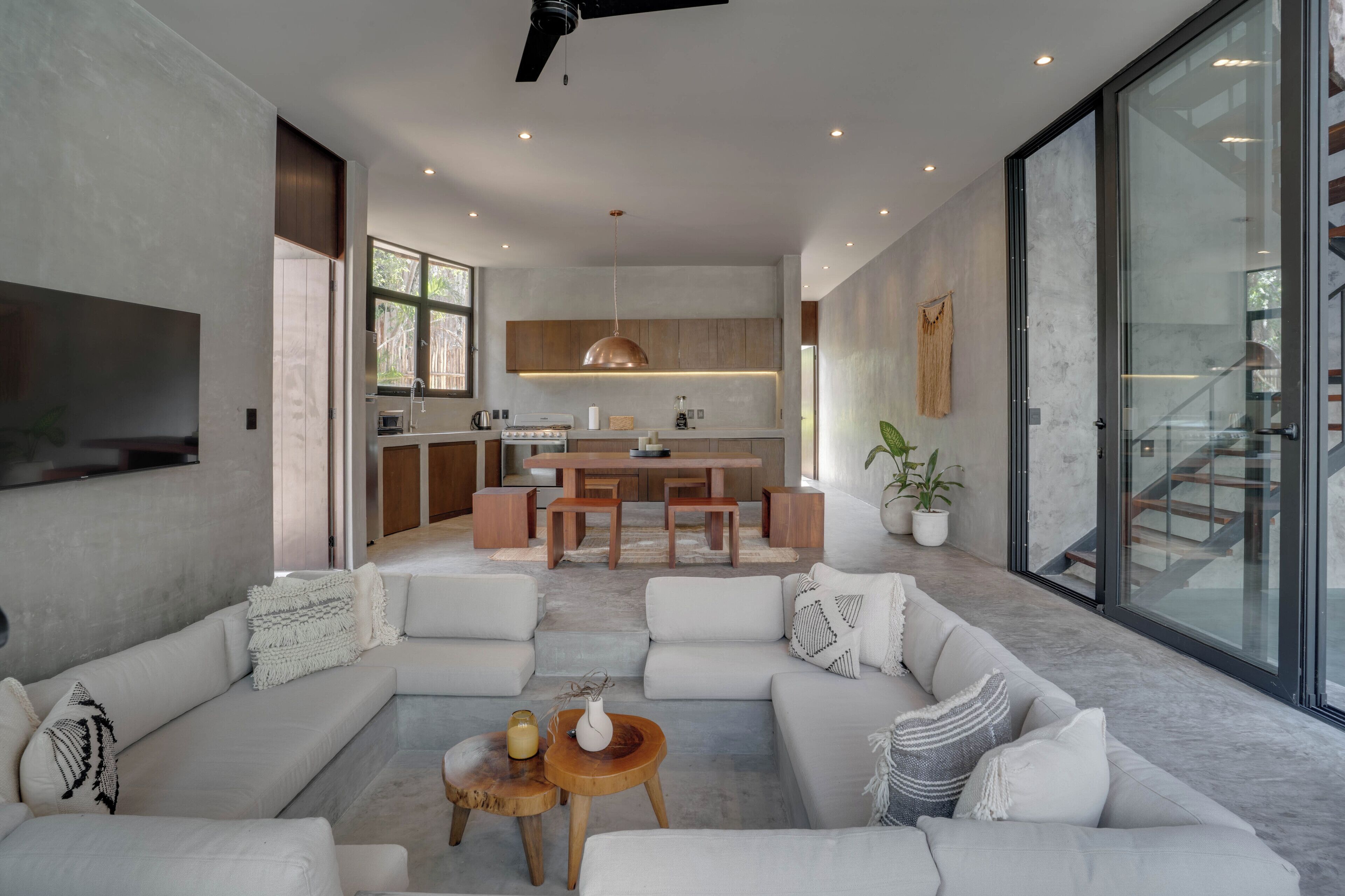 Una sala de estar moderna con un sofá modular grande, una mesa de centro y una cocina al fondo.
