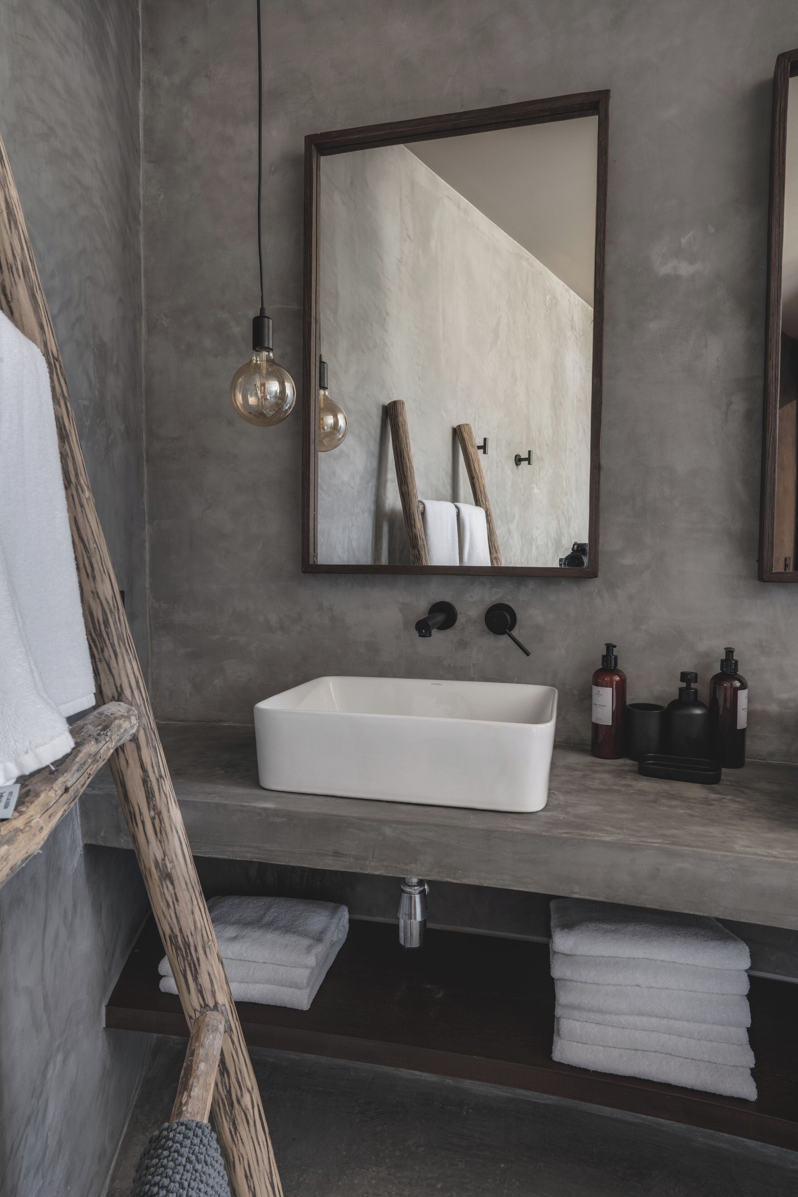 A bathroom with a white sink, a wooden ladder, and a mirror.
