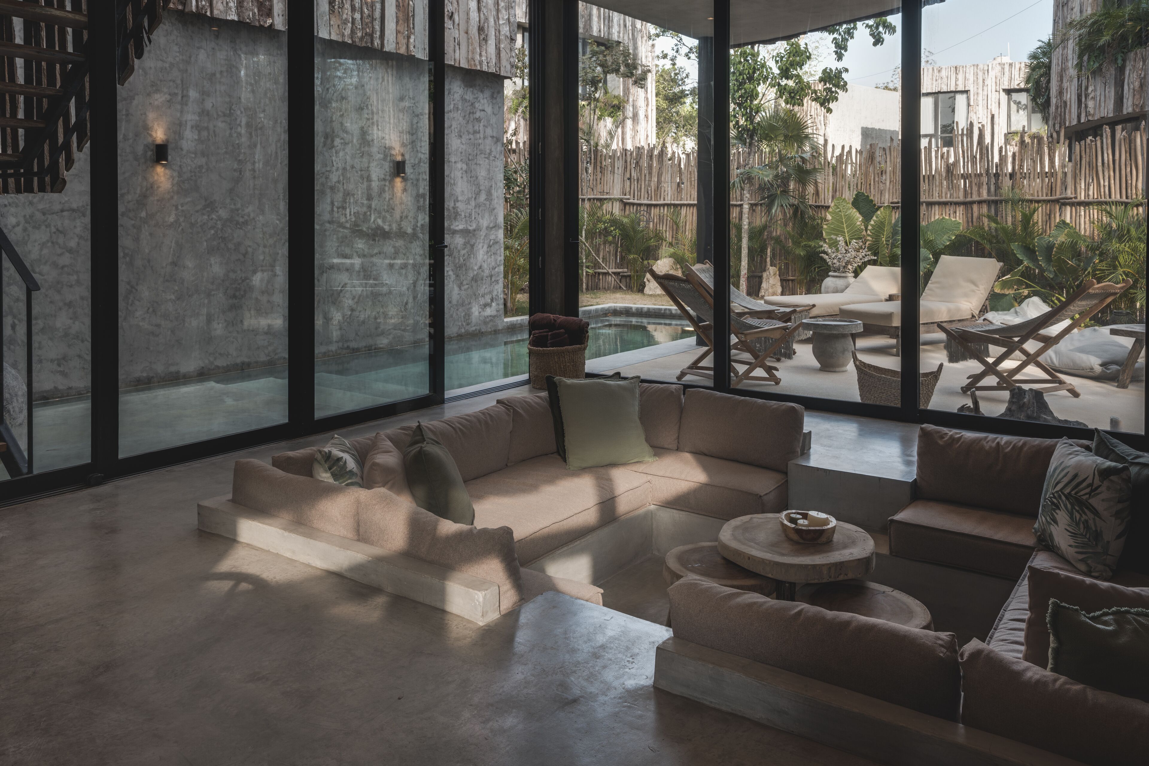 Un amplio salón con un ventanal que da a una piscina y un área de estar exterior.