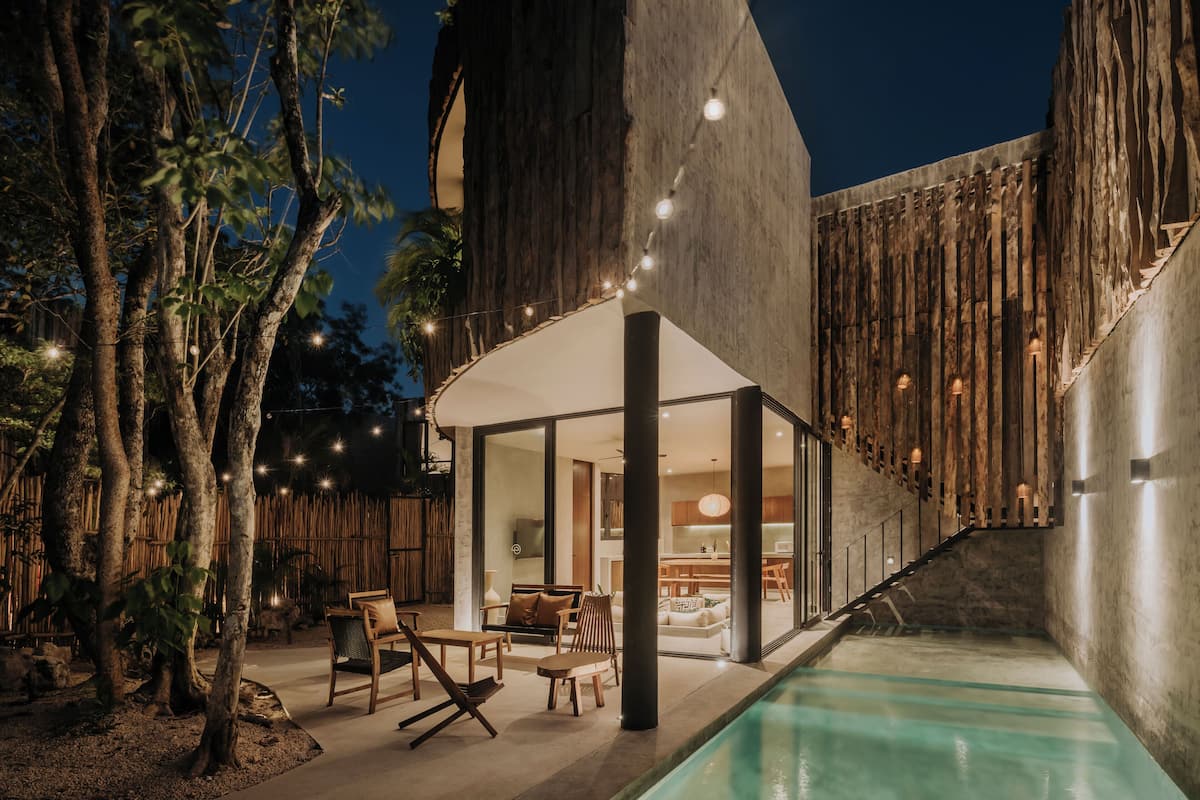 Uma área externa moderna com piscina, móveis de madeira e luzes de cordão.
