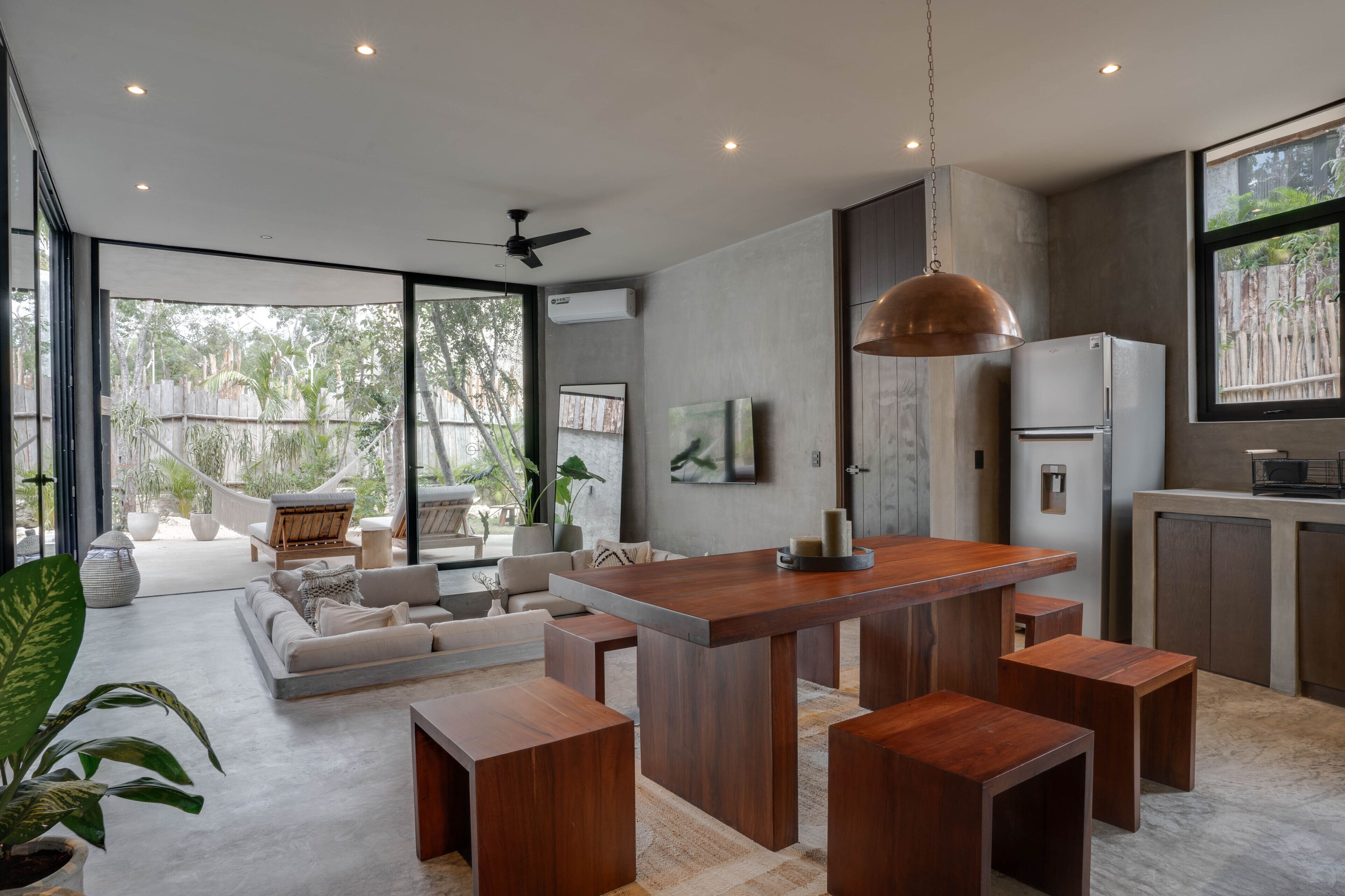 A modern kitchen with a central island, wooden stools, and a large pendant light.