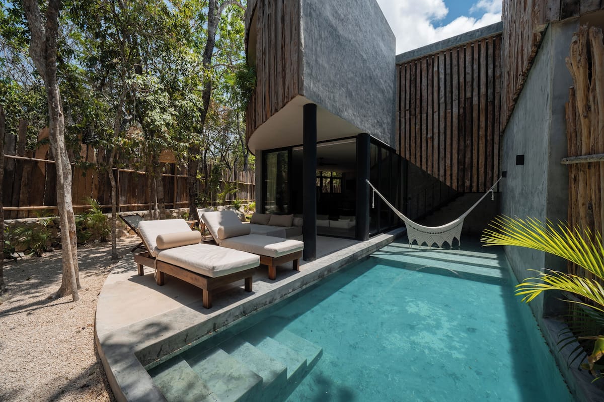 Uma área de piscina moderna ao ar livre, com espreguiçadeiras e uma rede.