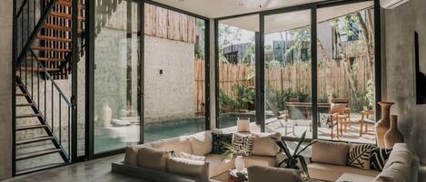 A spacious living area with a large sliding glass door leading to an outdoor patio, a built-in staircase, and a ceiling fan.