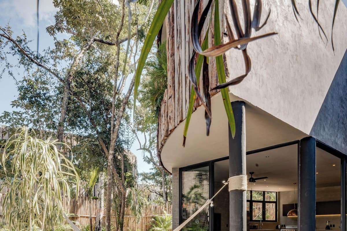 Uma área de piscina moderna ao ar livre, com uma rede, plantas em vasos e vista para o interior.