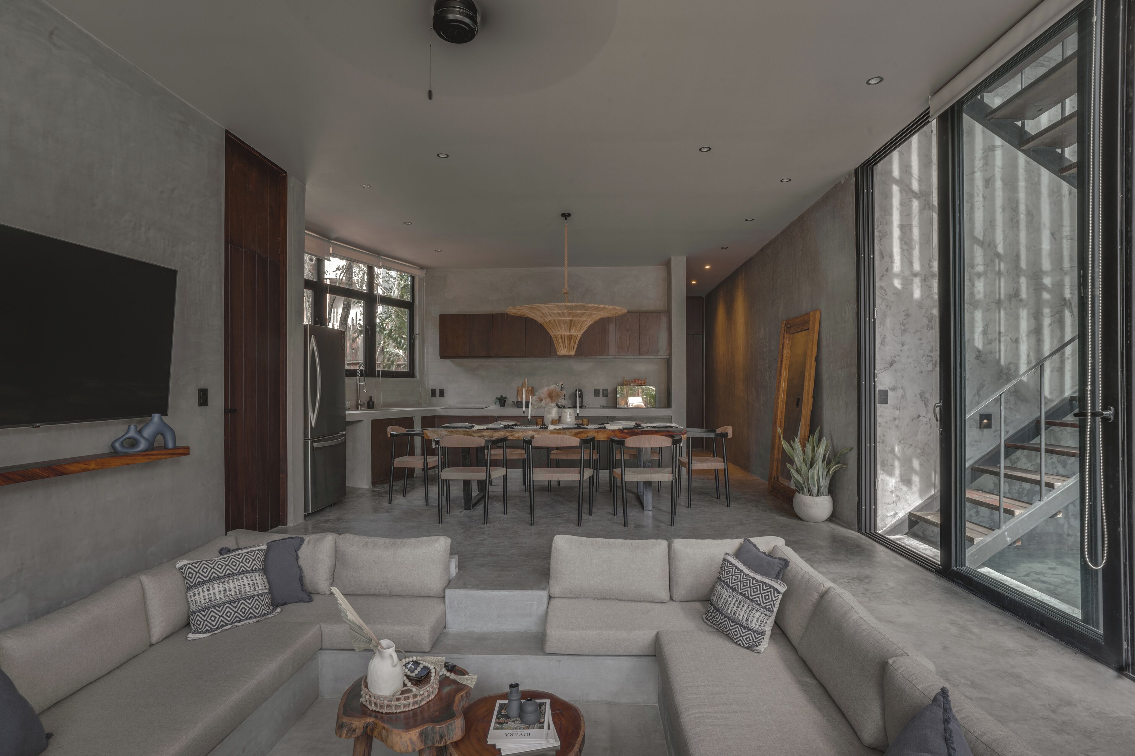 A modern living room with a large sofa, a dining area, and a kitchen.