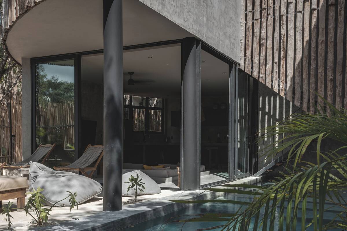 Uma área de piscina moderna com água cristalina, espreguiçadeiras e um muro de pedra.
