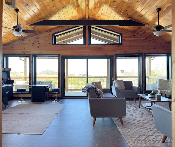 A spacious room with a high ceiling, large windows, and a ceiling fan.