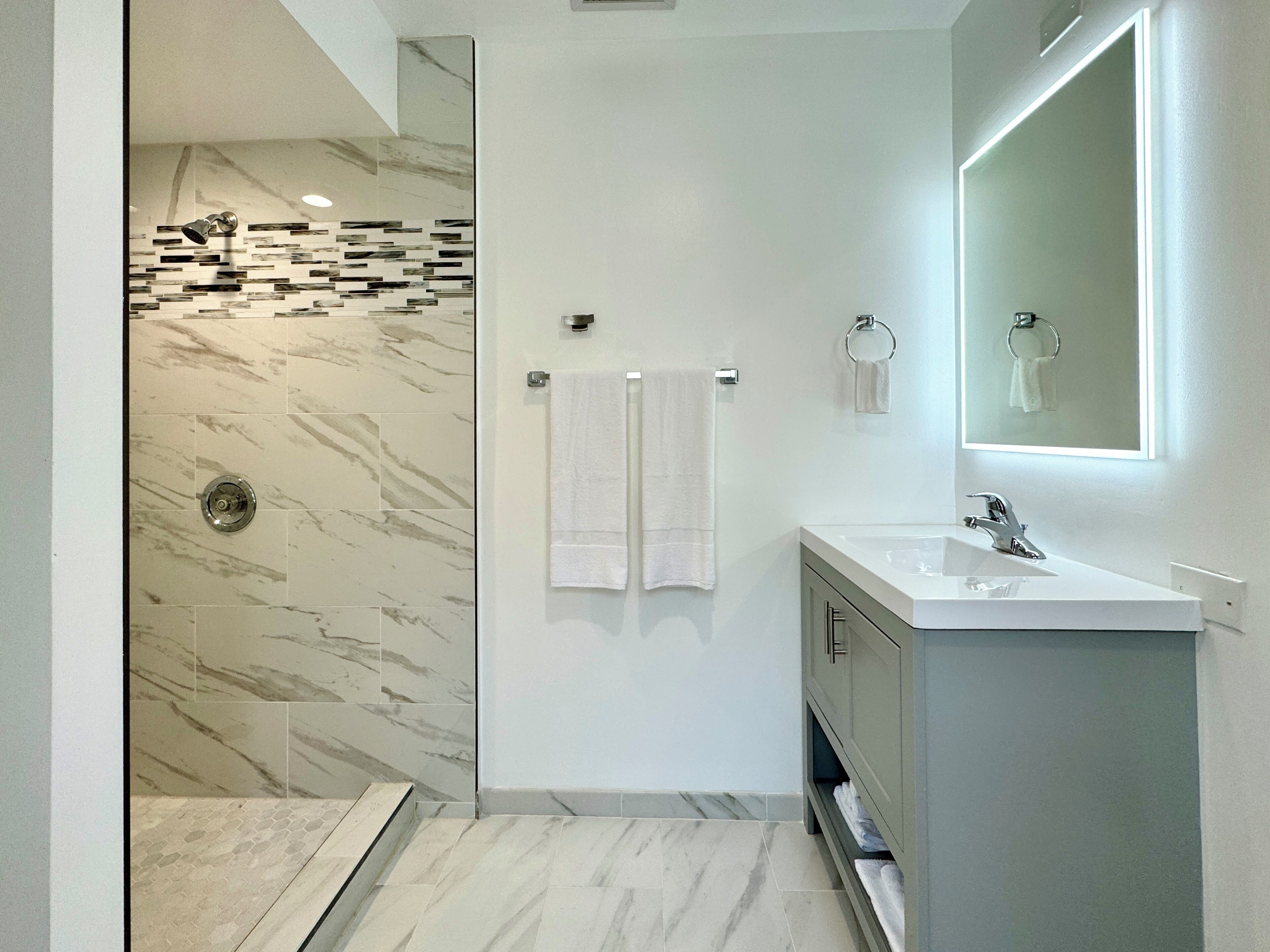 A modern bathroom with a shower, a sink, and a mirror.