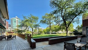 A patio area with outdoor seating and a view of a park with trees and a lawn. - The Gem Museum Suites (Evanston)
