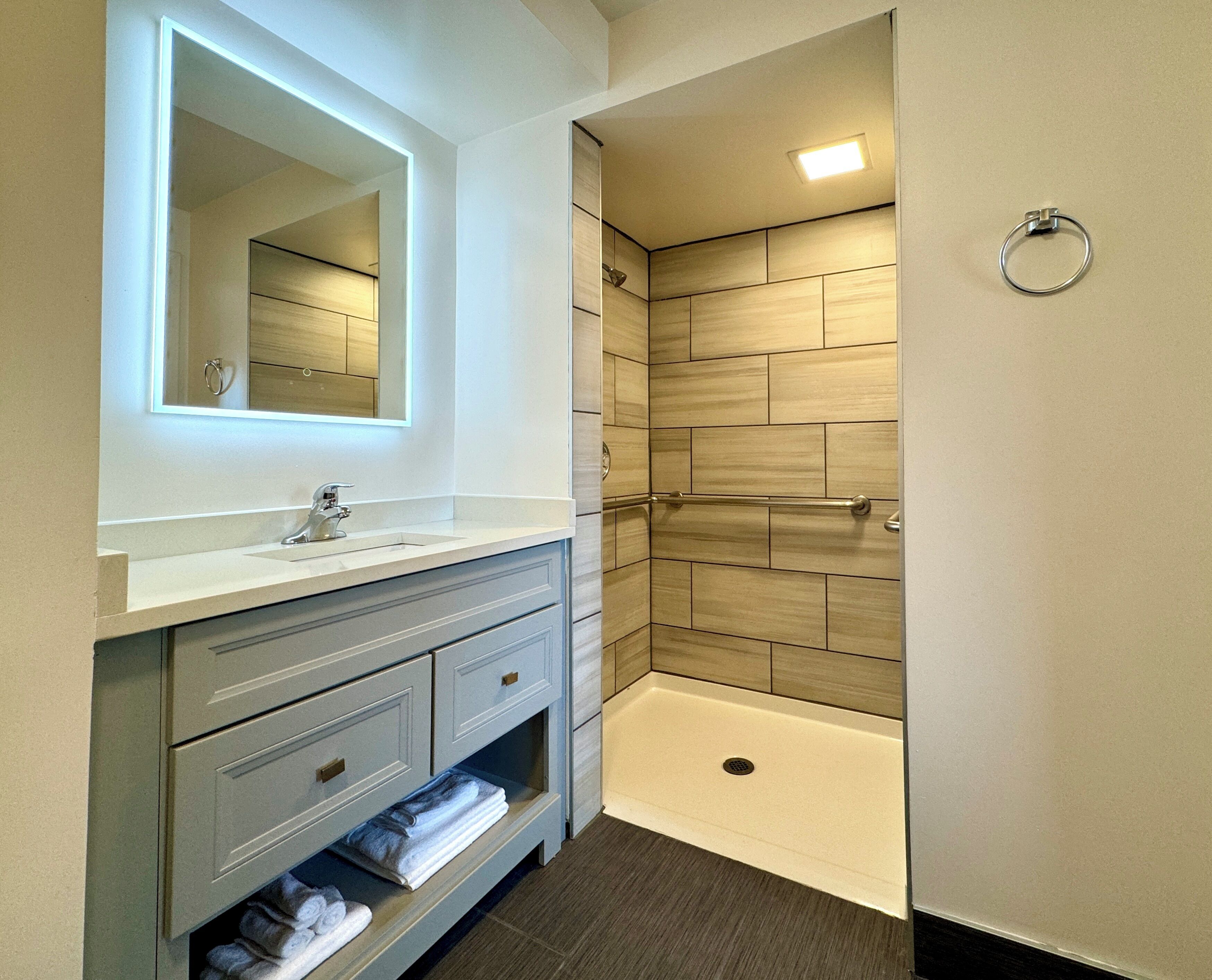 Une salle de bain moderne avec un meuble-lavabo, un miroir, une douche avec une porte en verre et un porte-serviettes.