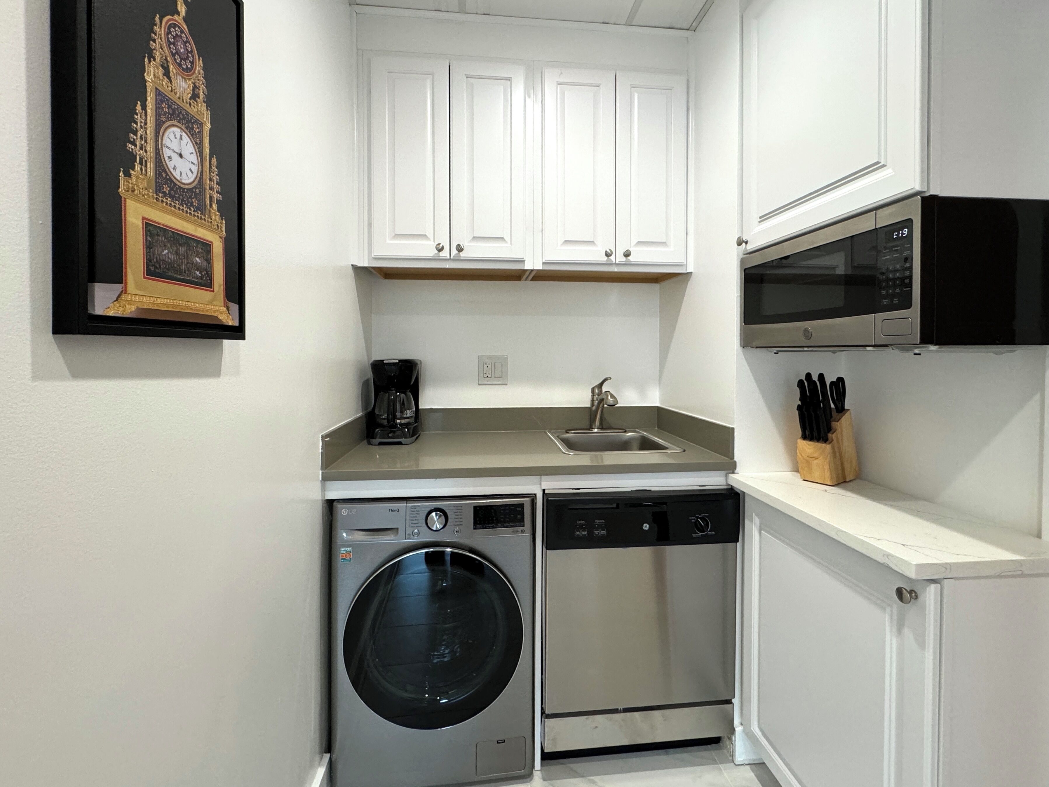 Une cuisine compacte équipée d’un lave-linge, d’un lave-vaisselle, d’un four à micro-ondes et d’une machine à café.