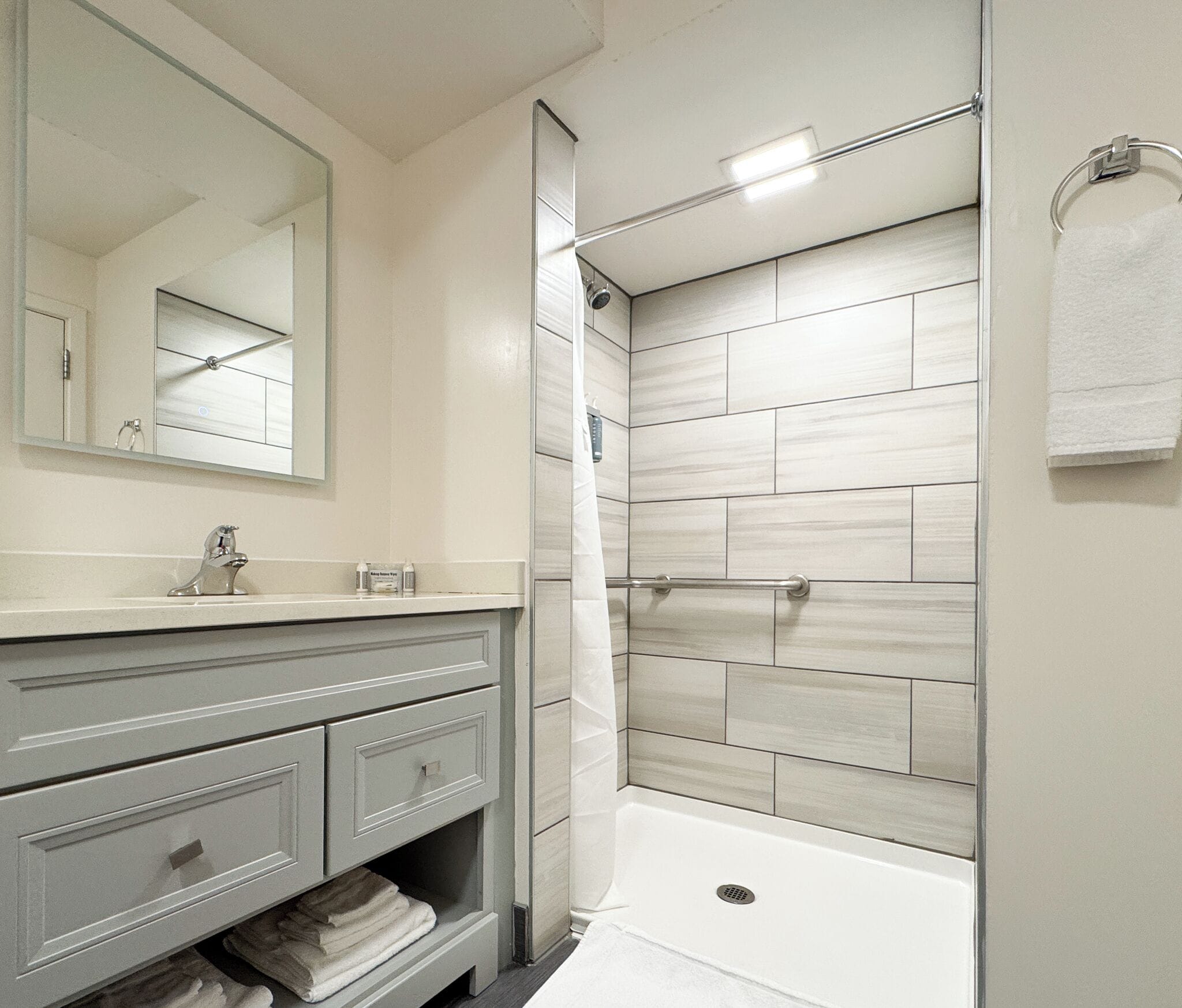 A modern bathroom with a vanity, mirror, shower, and bathtub.