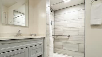 A modern bathroom with a vanity, mirror, shower, and bathtub.