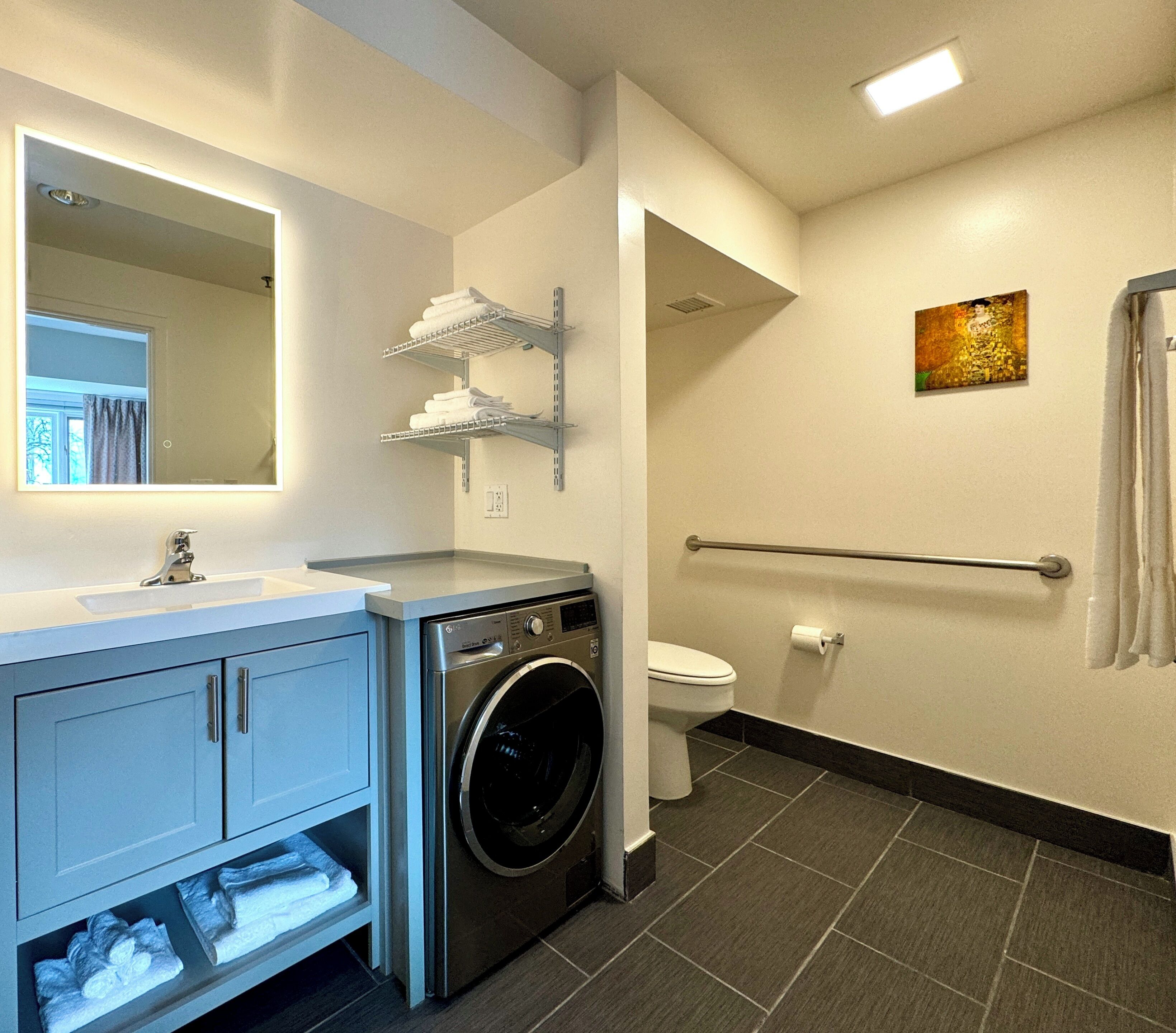A modern bathroom with a washing machine, a toilet, and a sink.