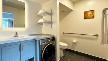 A modern bathroom with a washing machine, a toilet, and a sink.