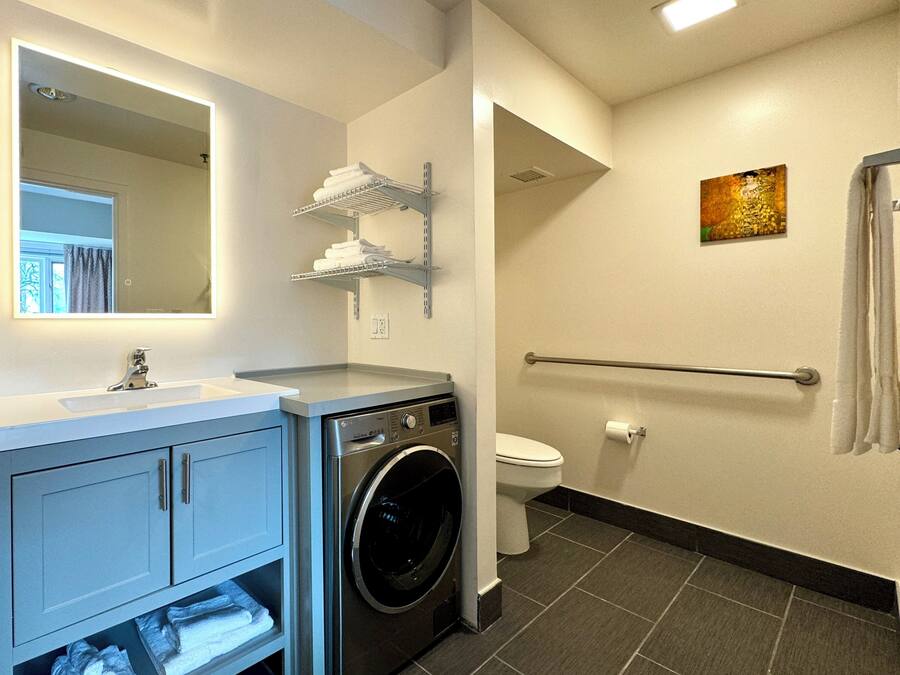 A modern bathroom with a washing machine, a toilet, and a sink.