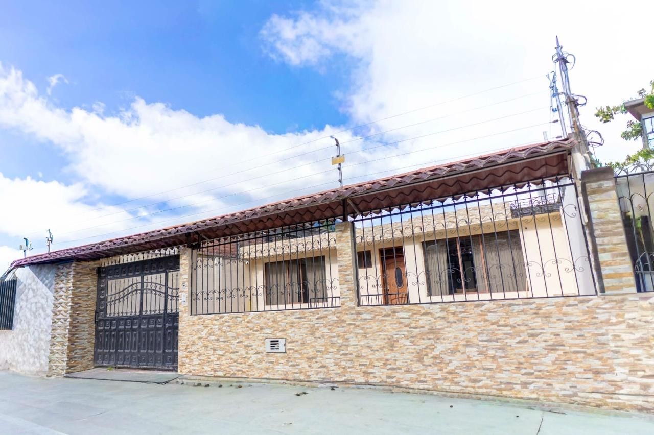 Un edificio de dos pisos con fachada de piedra, una reja metálica y techo de tejas.