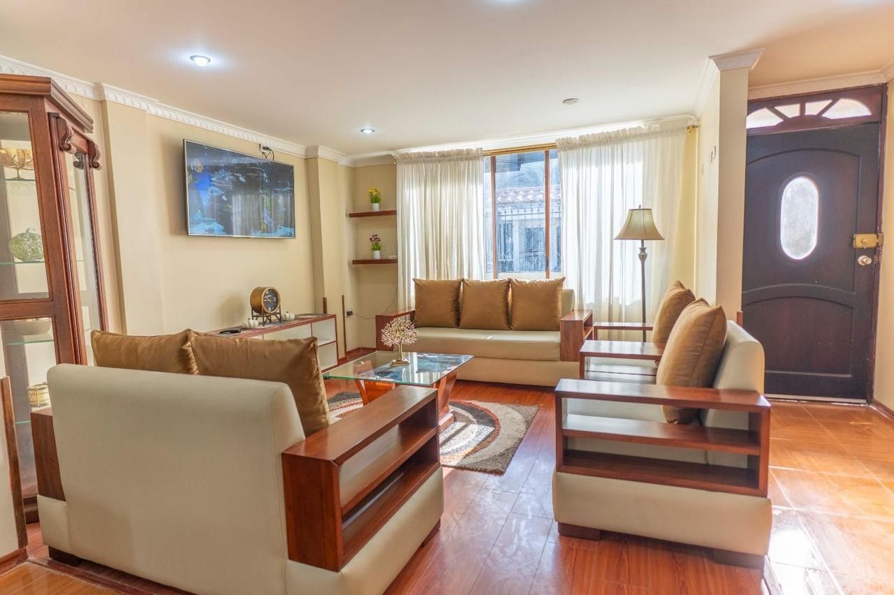 Un salon comprenant un canapé, des fauteuils, une table basse et un téléviseur fixé au mur.