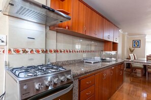 Une cuisine avec des meubles en bois, une cuisinière à gaz et un dosseret carrelé.