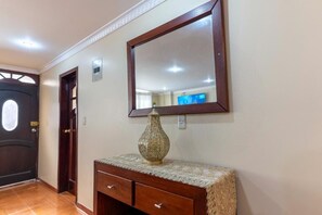 A hallway with a wooden door, a mirror, and a decorative vase on a console table.