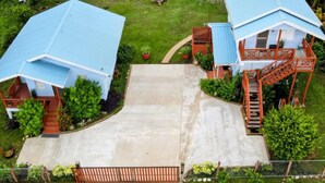 A two-story house with a blue roof, a covered porch, and a staircase leading to the upper floor. - Elle's 2 BR/2 bathroom, home in San Ignacio. Minutes from town & Maya Ruins (Cayo District)