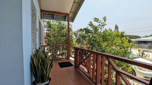 A balcony with a potted plant, a wooden railing, and a view of trees and buildings. - Elle's 2 BR/2 bathroom, home in San Ignacio. Minutes from town & Maya Ruins (Cayo District)