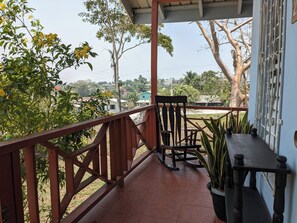 Relax in a serene outdoor space surrounded by trees, featuring a comfortable rocking chair and a potted plant.