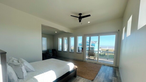 A bedroom with a bed, a ceiling fan, and a view of the outside. - Gated 5 Bed • 4 Bath • Private Beach Access • Early Check-In & Late Checkout (Bolivar Peninsula)