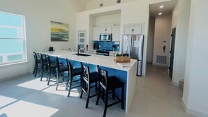 A modern kitchen with a central island, bar stools, and built-in appliances. - Gated 5 Bed • 4 Bath • Private Beach Access • Early Check-In & Late Checkout (Bolivar Peninsula)